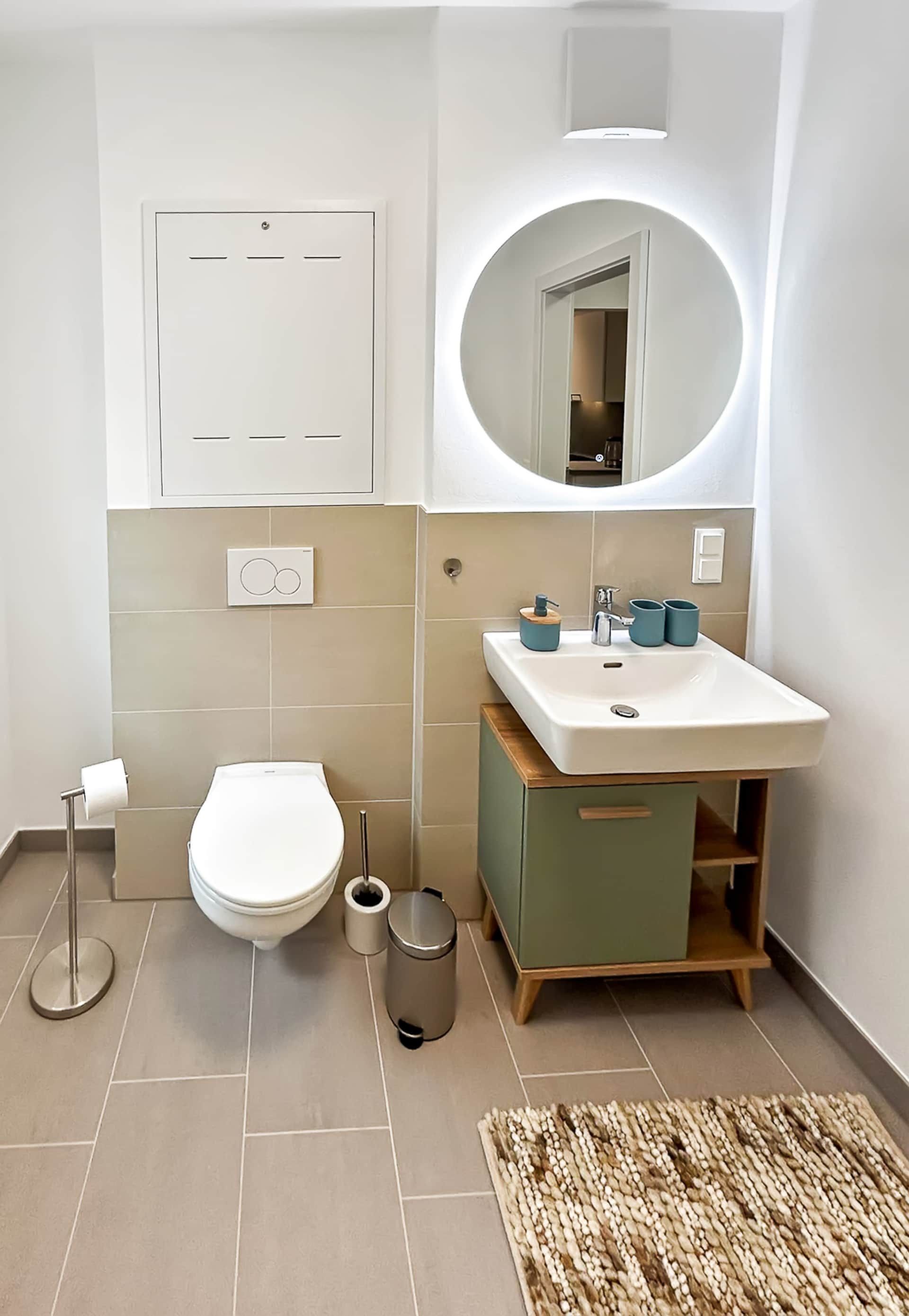 WC with washbasin, illuminated mirror and vanity unit.