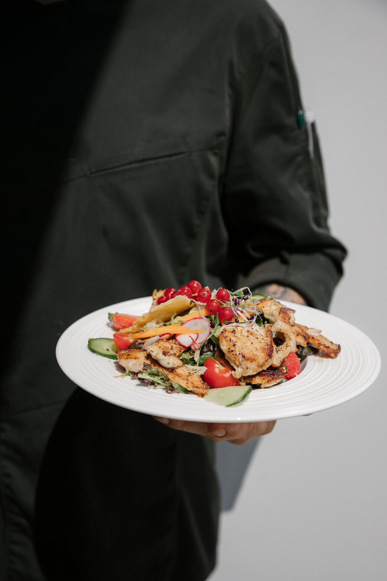Kellner präsentiert einen Salatteller mit Hühnerfleisch im Lahning-Inn am Schneeberg