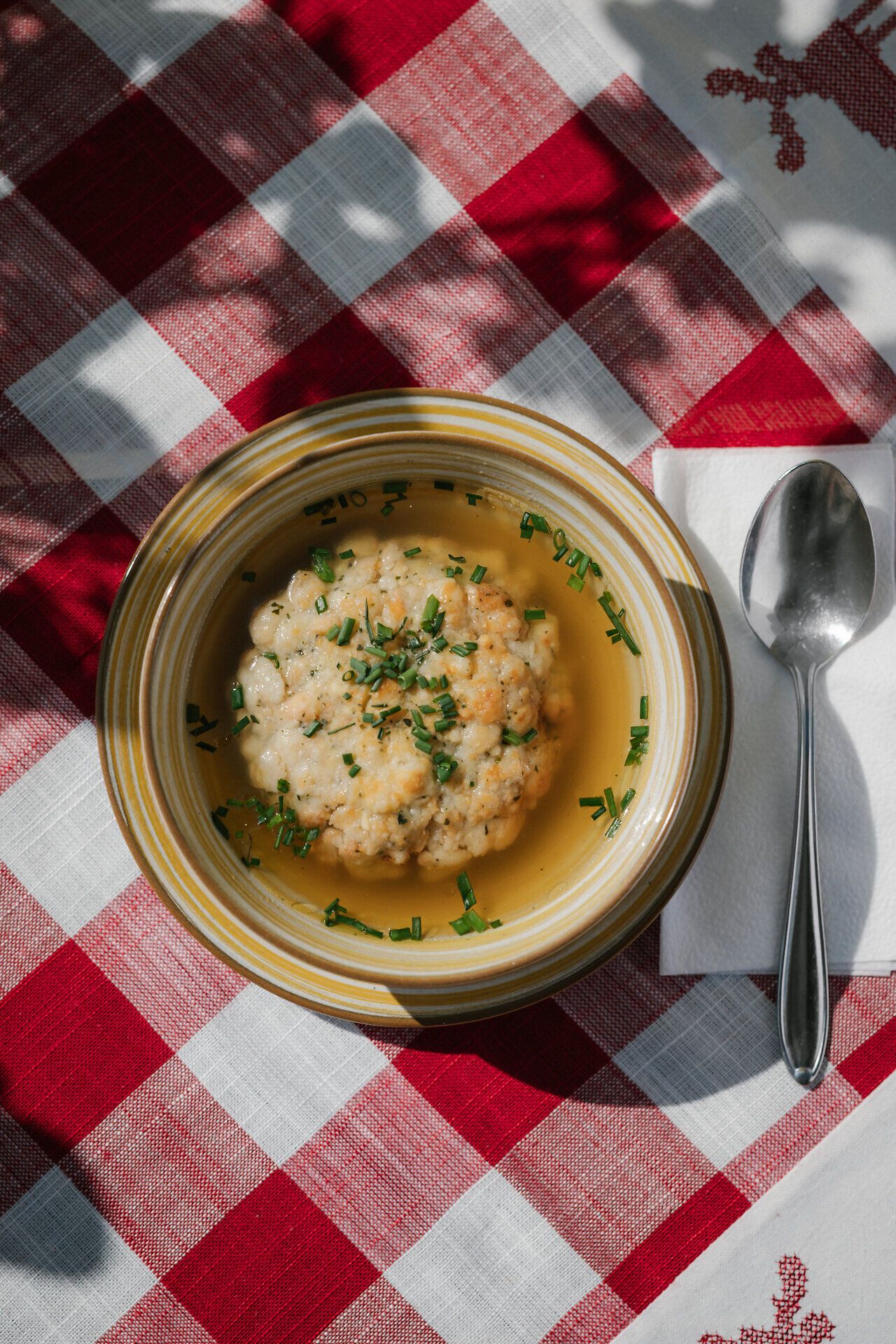 Klare Suppe mit Grießnockerl in einem Teller auf karierter Tischdecke beim Damböckhaus am Schneeberg