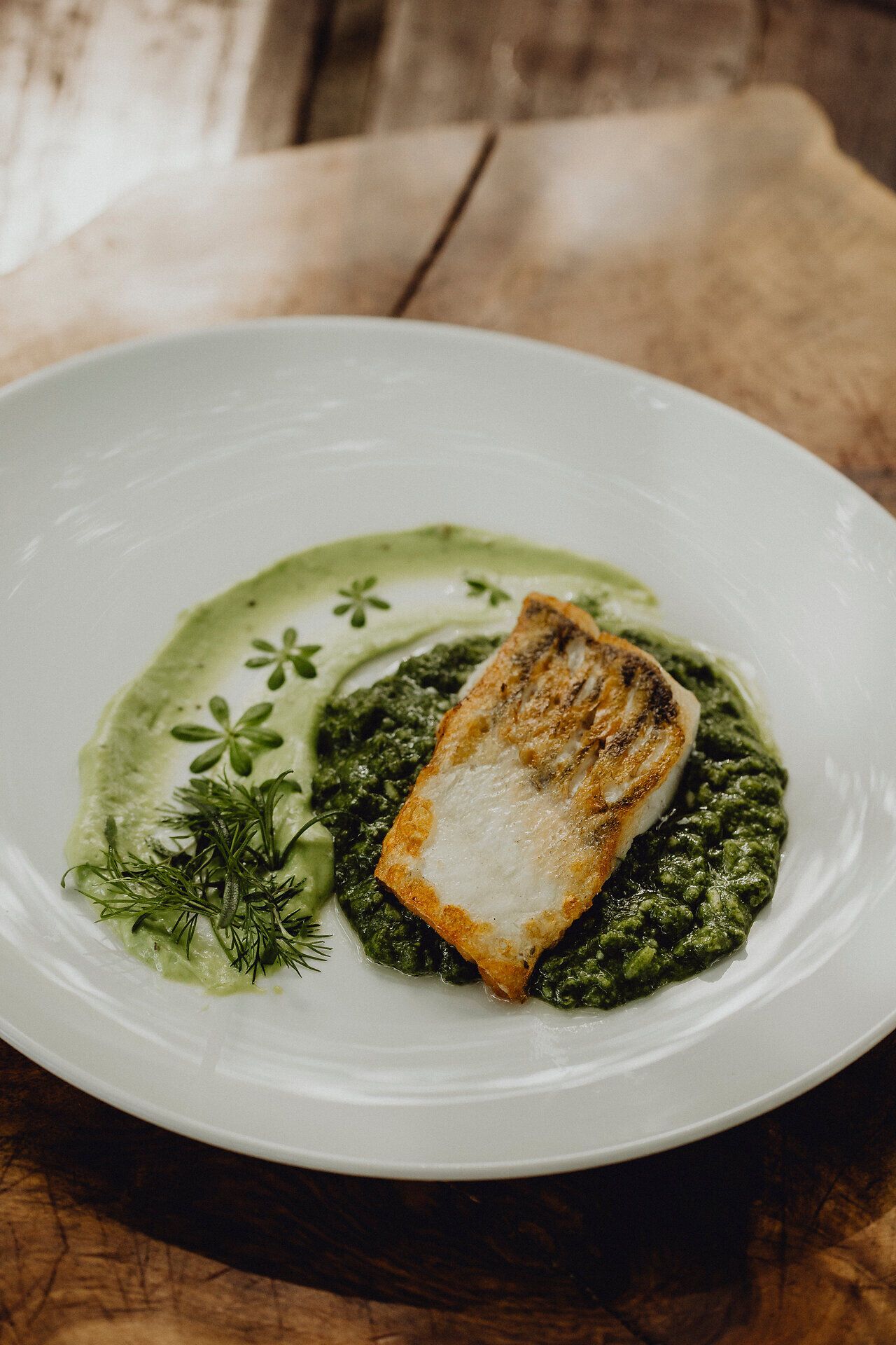 Ein köstliches Zanderfilet, perfekt kross gebraten, ruht auf einem Bett aus cremigem Spinat-Risotto, verfeinert mit einer Basilikumcreme. Diese harmonische Kombination verspricht ein unvergessliches Geschmackserlebnis inmitten der malerischen Wiener Alpen.