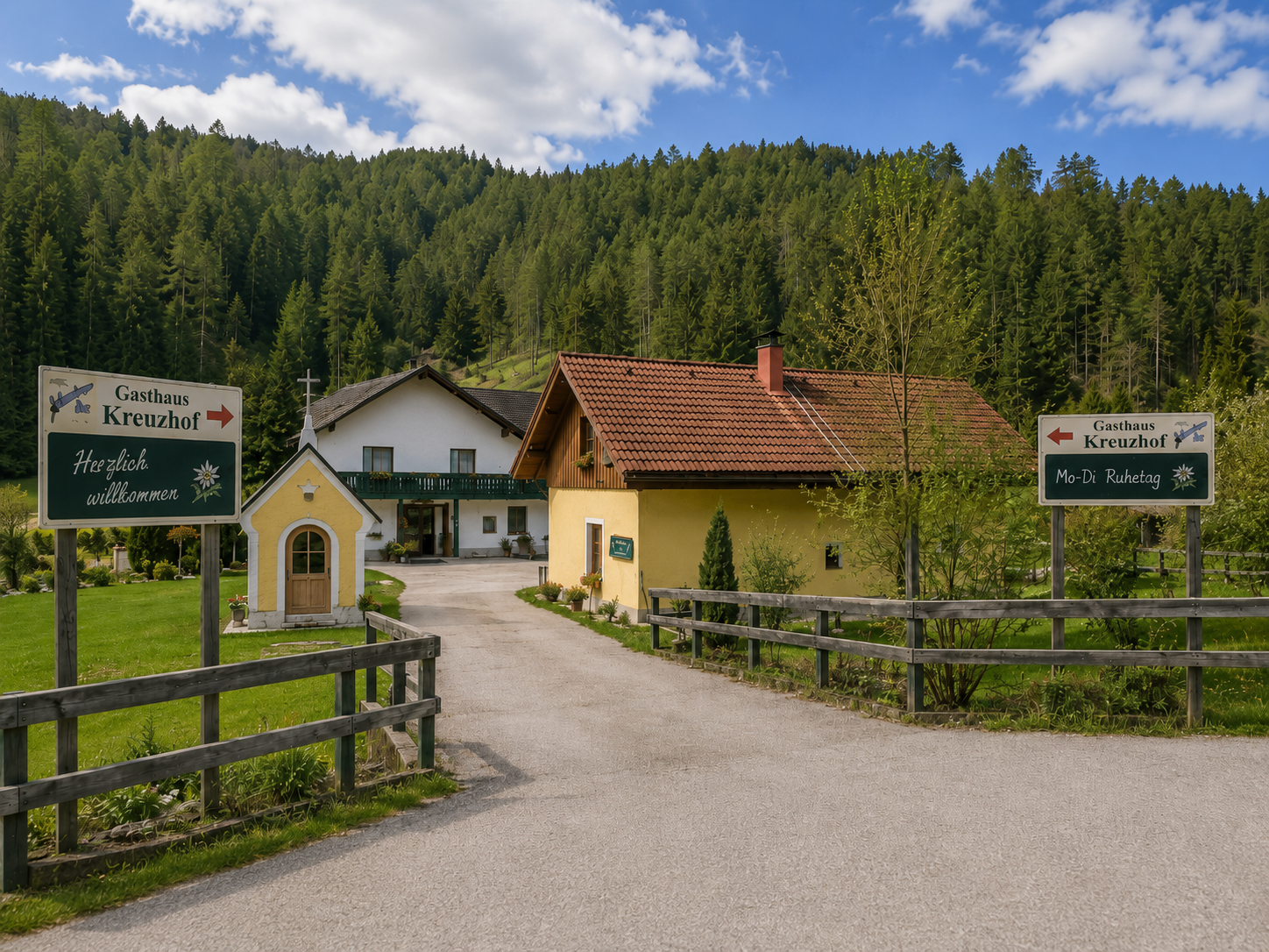 Eingang zum Gasthaus Kreuzhof mit Schildern und Kapelle, umgeben von Wald.