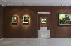 Innenansicht eines Museums mit Gemälden an braunen Wänden.