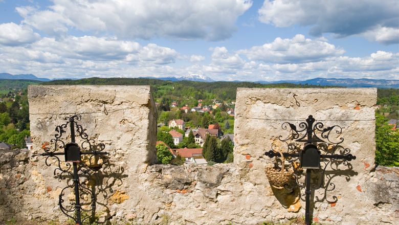 Aussicht von einer alten Steinmauer auf eine ländliche Landschaft mit Bergen im Hintergrund.