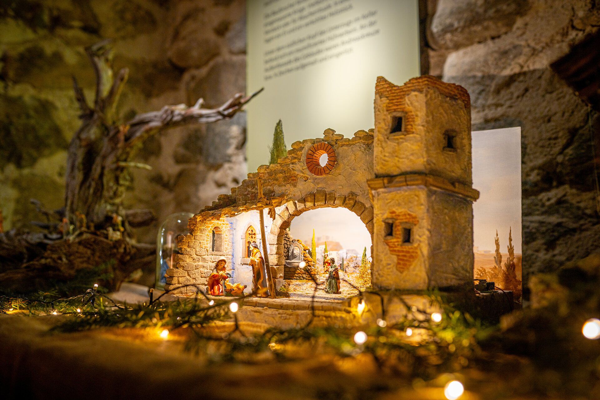 Detailaufnahme einer beleuchteten Krippenlandschaft mit Burg und Figuren in warmem Licht.