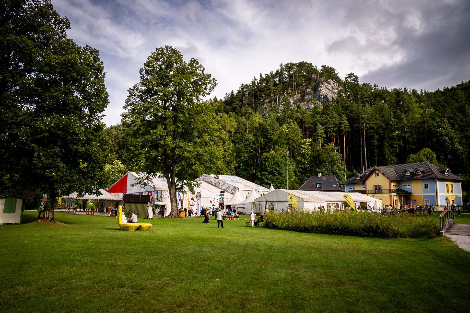 Das Festzelt der Raimundspiele Gutenstein steht in einem kleinen Park. Besucher des Festivals stehen davor.