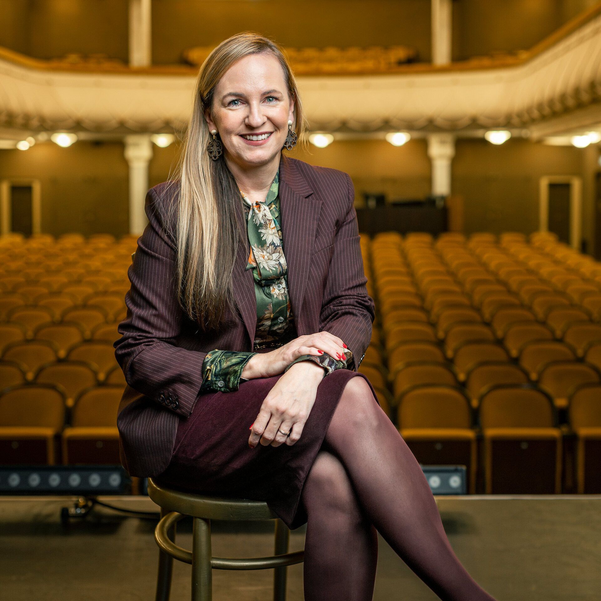 Maria Grossbauer vom Stadttheater Wiener Neustadt sitzt auf einem goldenen Sessel auf der Bühne des Stadttheater.