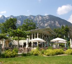 Orangerie Schloss Wartholz, davor eine Terrasse mit Sonnenschirmen und dahinter ein Berg