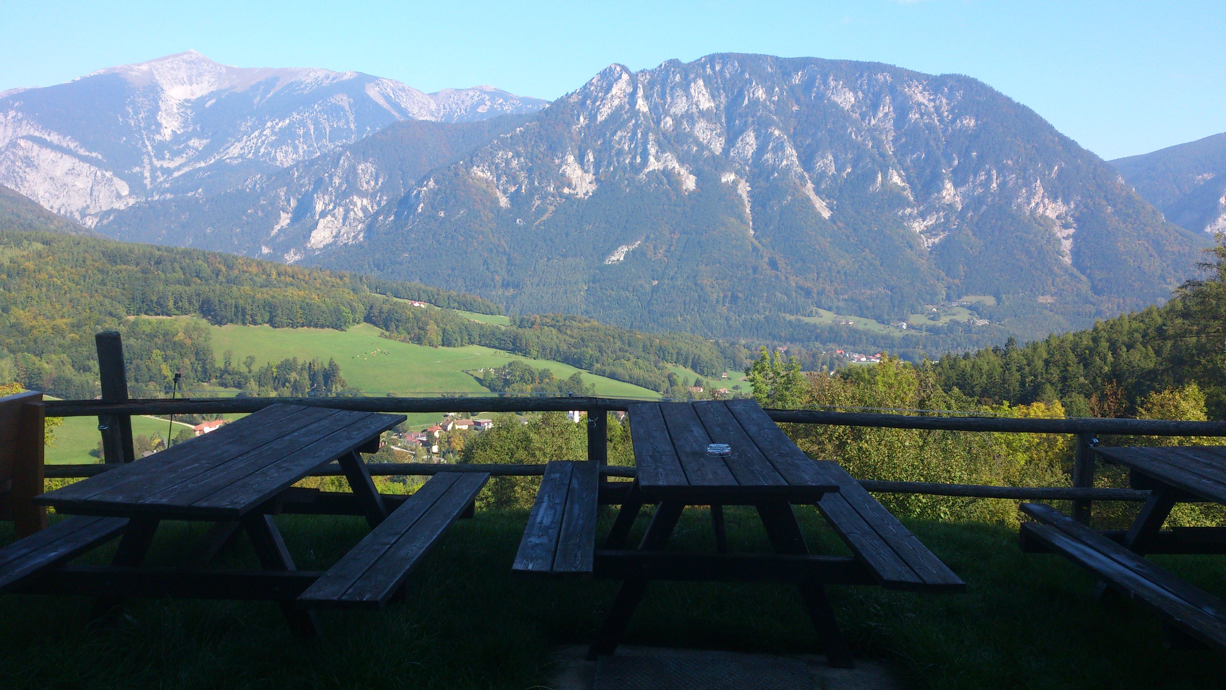 Holzbänke mit Blick auf bewaldete Berge und Täler.