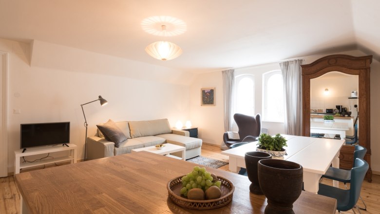 Modernes Wohnzimmer mit Sofa, Esstisch und Spiegel.