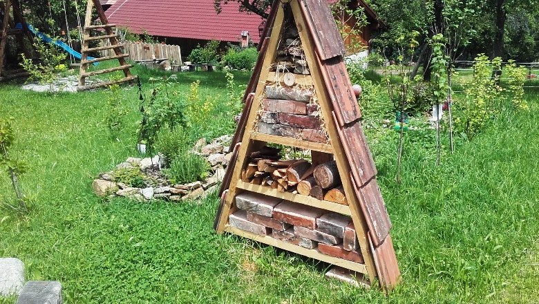 Ein Insektenhotel in einem Garten mit Rasen und Bäumen.