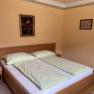 A cozy double room with a double bed, green bed linen and two pictures on the wall.
