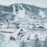 Snow-covered village with ski resort in the background.