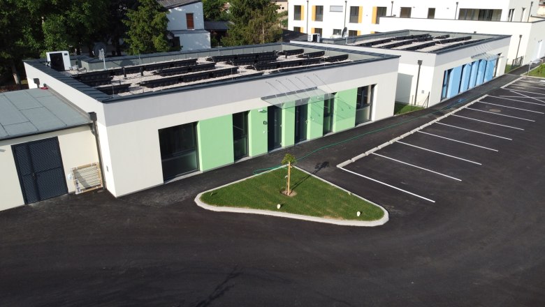 Exterior view of modern vacation bungalows with green and blue paint, parking lot and small lawn area.