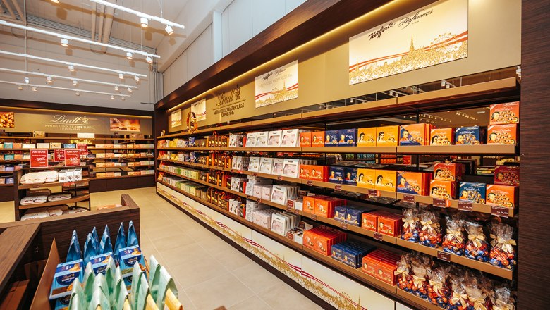 Innenansicht eines Lindt & Sprüngli Shops mit Regalen voller Schokolade und Süßigkeiten.