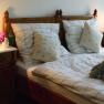 Cozy double room with wooden furniture, bed with checkered bedding, bedside tables and lamps.