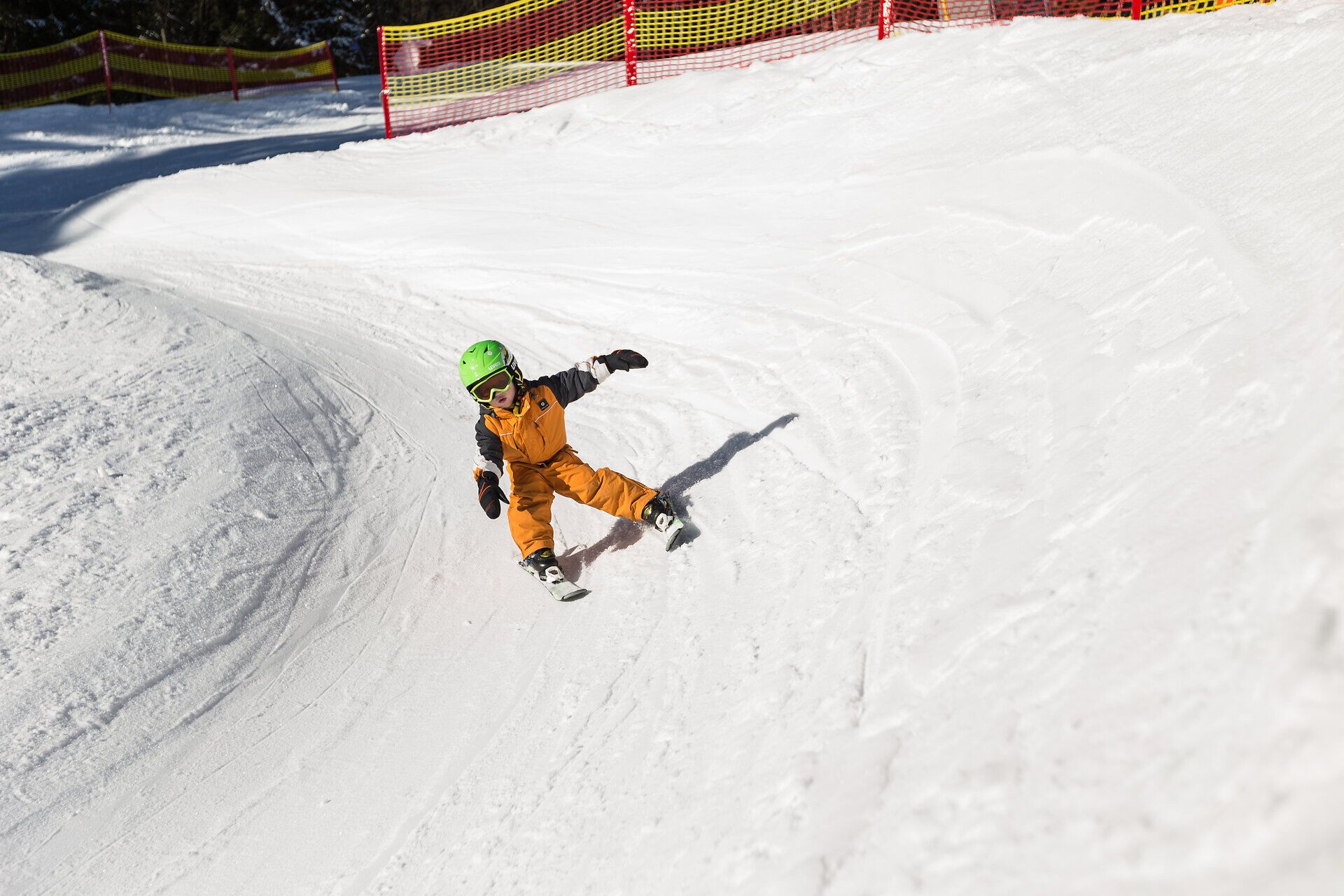 Ein kleiner Skifahrer gleitet mit Freude über die schneebedeckte Piste und genießt die winterliche Freiheit. Die strahlende Sonne und die frische Bergluft schaffen eine perfekte Kulisse für unvergessliche Familienmomente im Schnee.