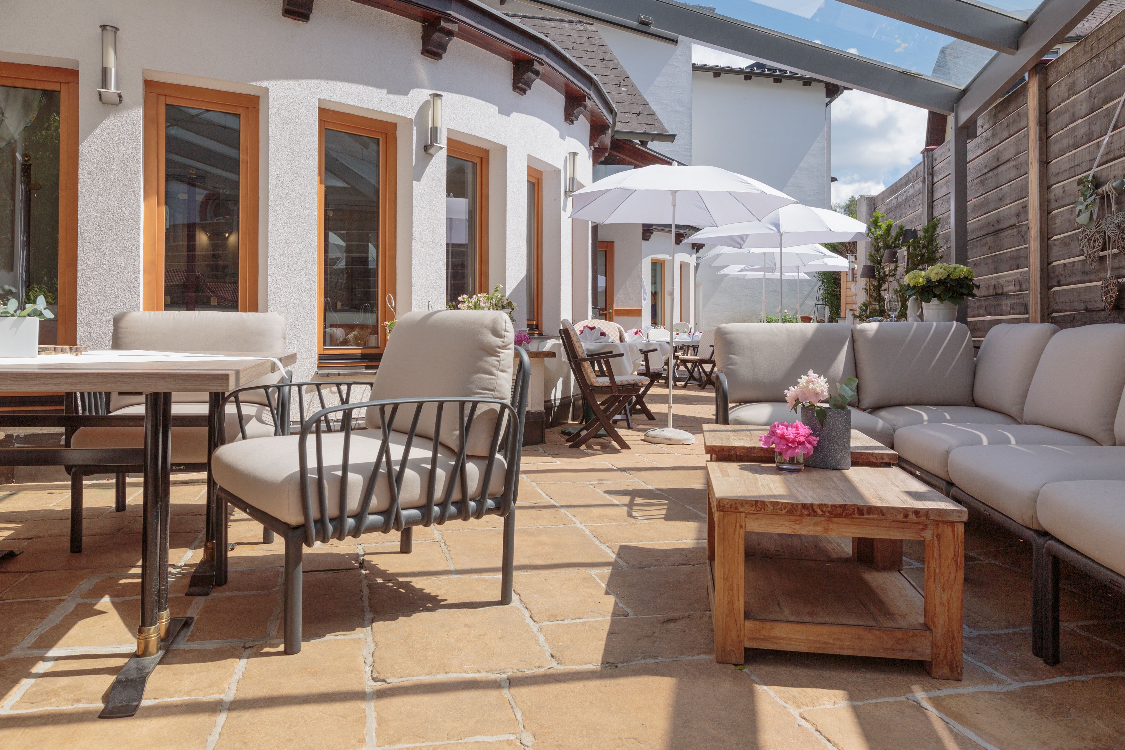 Eine gemütliche Terrasse mit modernen Möbeln, Sonnenschirmen und Pflanzen, die eine entspannte Atmosphäre schaffen.