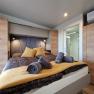 Modern bedroom with double bed, yellow pillows and towels, wooden wardrobes and air conditioning.