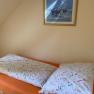A bed with colorful bed linen in a single room, with a framed picture on the wall above it.