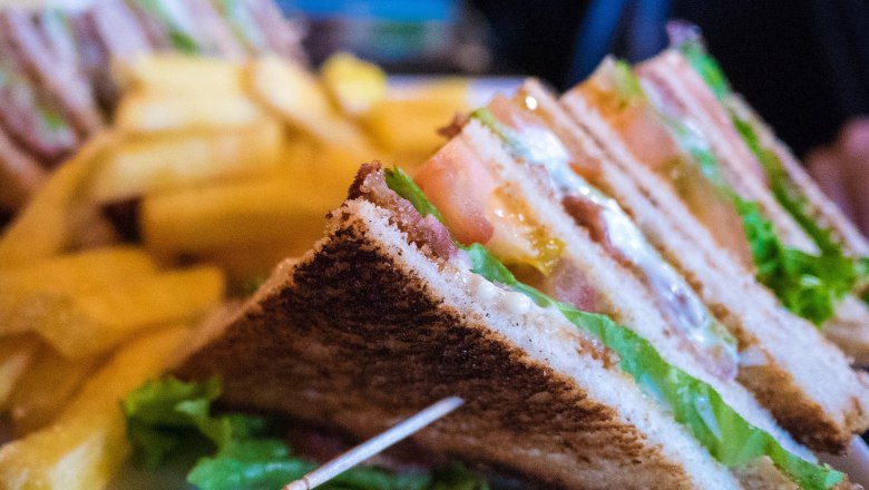 Close-up of club sandwiches with French fries in the background.