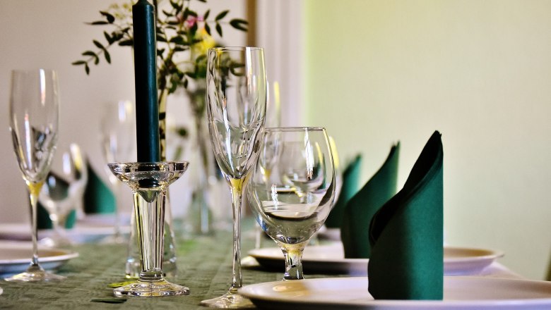 Gemütlich speisen, © gemeinfrei Eleganter Tisch mit Weingläsern, Kerze und gefalteten Servietten.