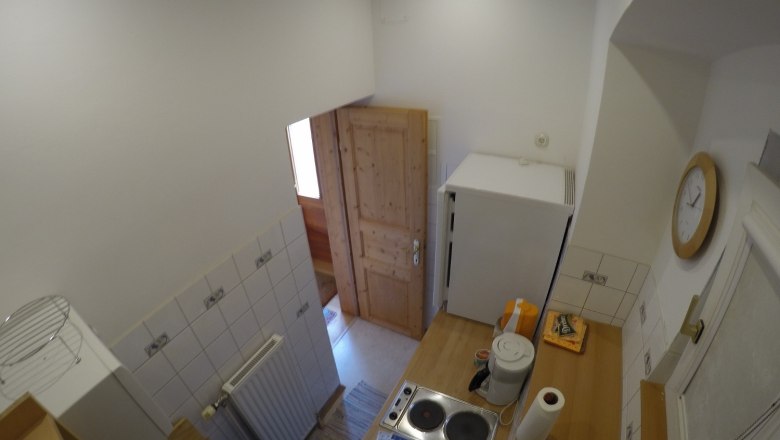 Kleine Küche mit Herd, Kühlschrank und Holztür.