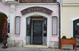Eingang der Cavallo Café-Bar mit rosa Fassade und Holzschild.