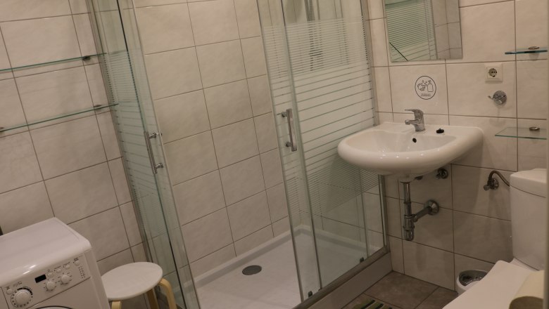 Modernes Badezimmer mit Dusche, Waschbecken, Toilette und Waschmaschine.