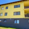 Yellow building with brown windows and balconies, blue sky in the background.