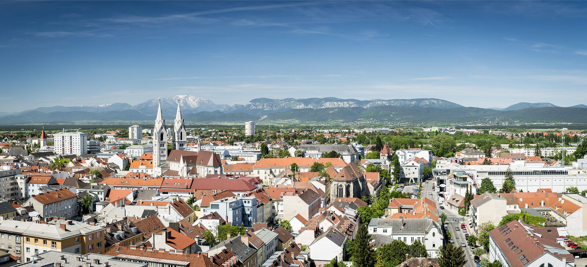 Blick auf die Stadt Wiener Neustadt und die dahinterliegende Berglandschaft mit Rax, Schneeberg und Hohe Wand.