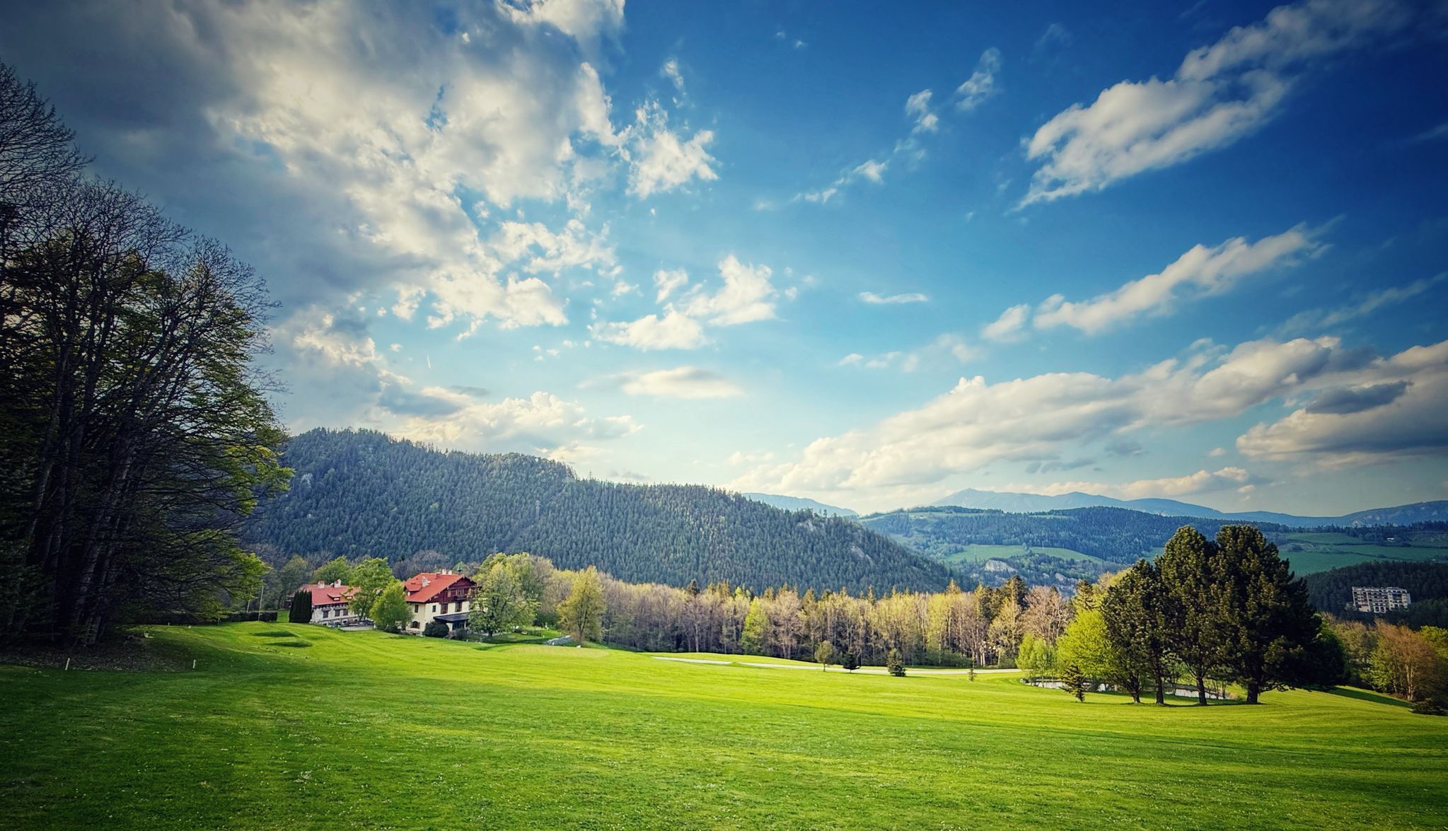 Blick auf den Golfplatz Semmering und im Hintergrund das weitgehende Schwarzatal mit bewaldeten Hügeln