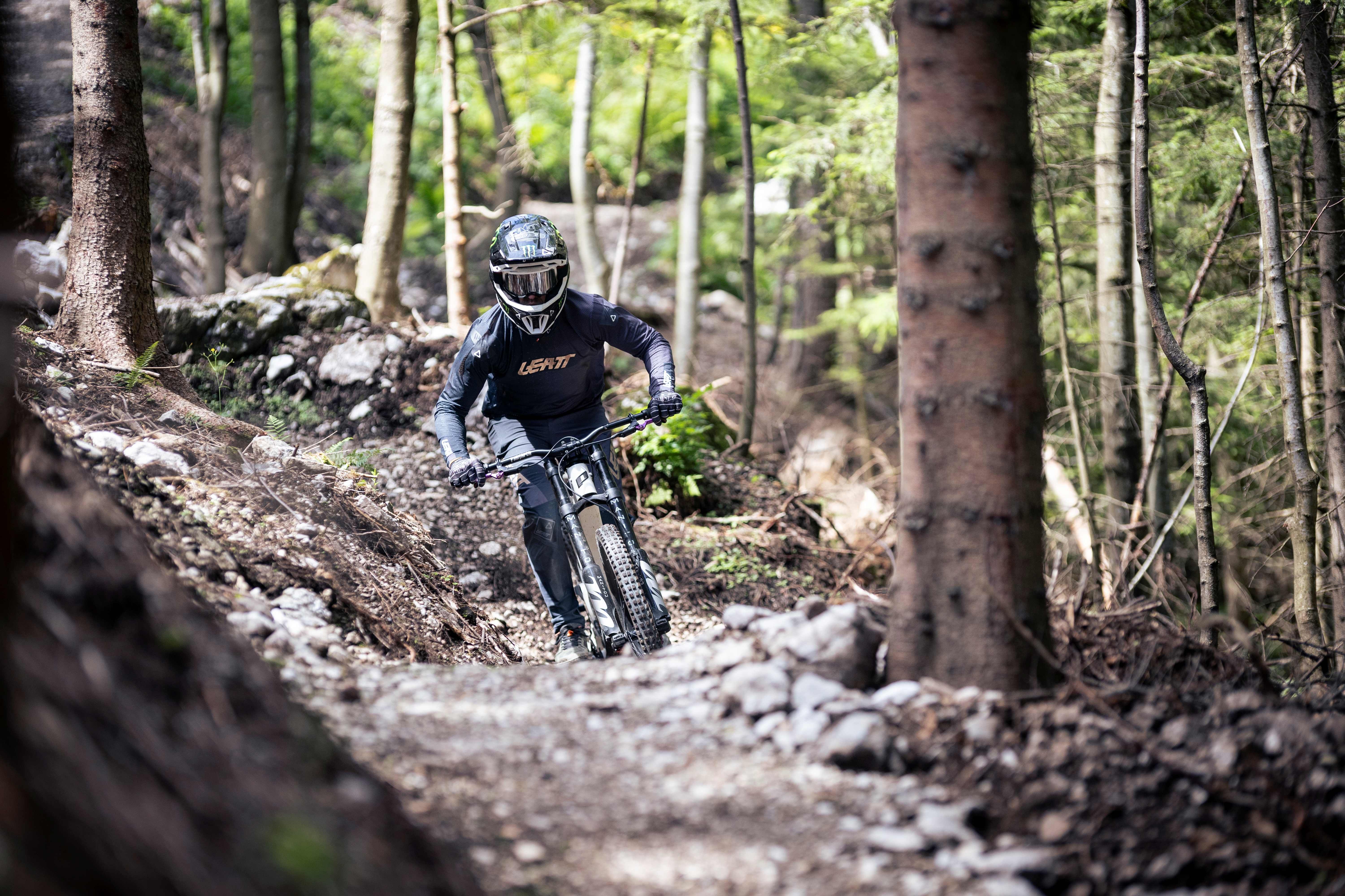 Ein Mountainbiker fährt mit hoher Geschwindigkeit durch einen Waldpfad.