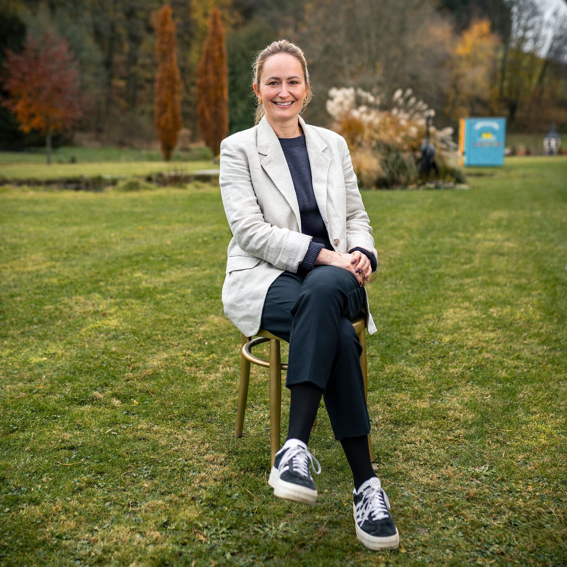 Tessa Erker-Tegetthoff, intendantin des Fabelhaft Festivals, sitzt auf einem goldenen Sessel auf einer grünen Wiese.