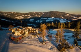 Alpengasthof Enzian in verschneiter Berglandschaft bei Sonnenuntergang.