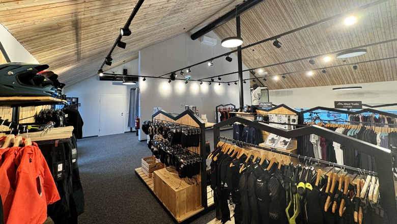 Interior view of a sports store with wooden ceiling and clothes on racks.