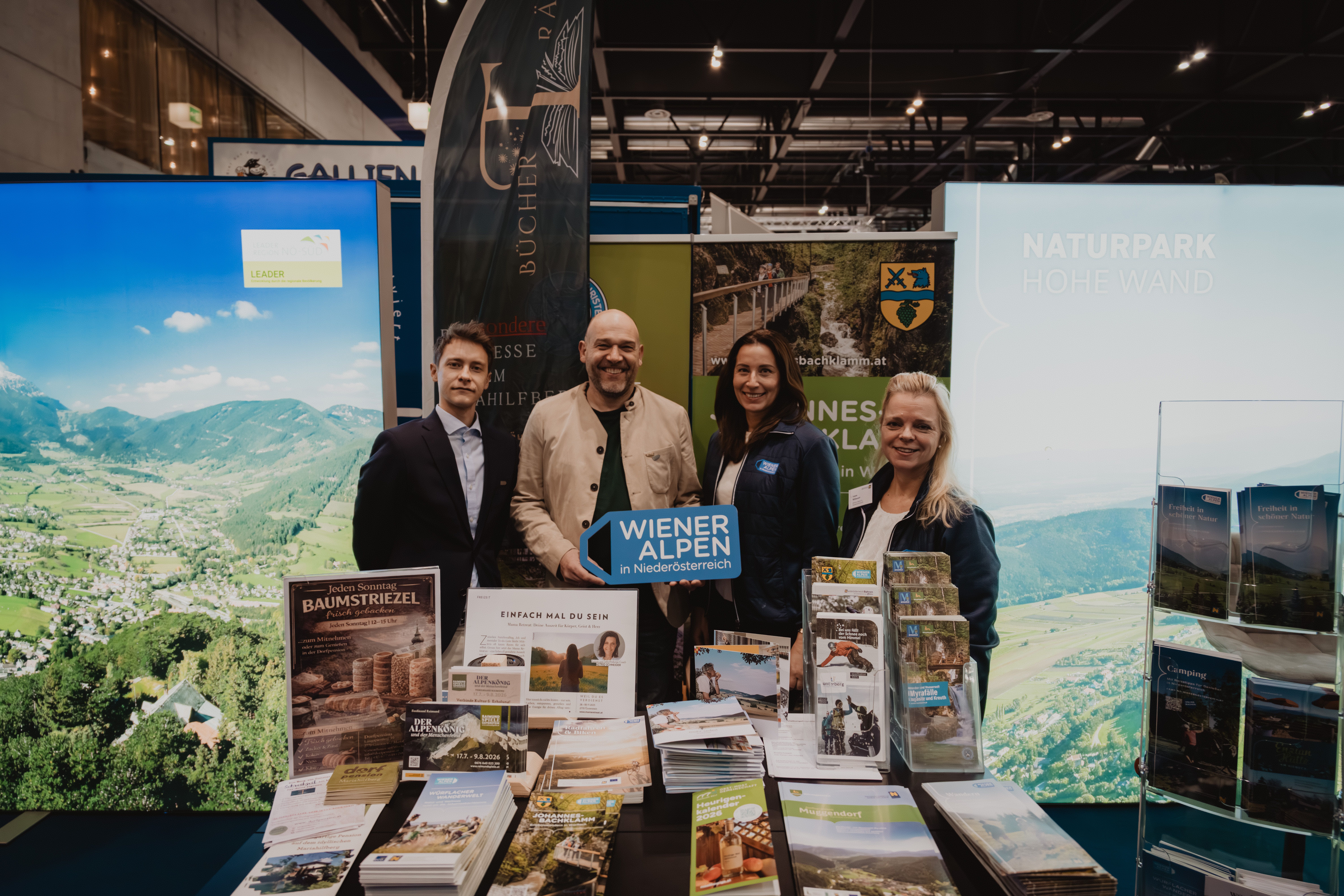 Vier Personen mit dem Schild Wiener Alpen in Niederösterreich hinter Prospektaufstellern 