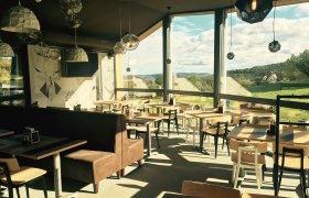 Innenansicht der Wexl Lounge mit großen Fenstern und Blick auf die Landschaft.