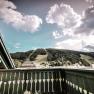 View from a balcony of a green mountain landscape with clouds in the sky.