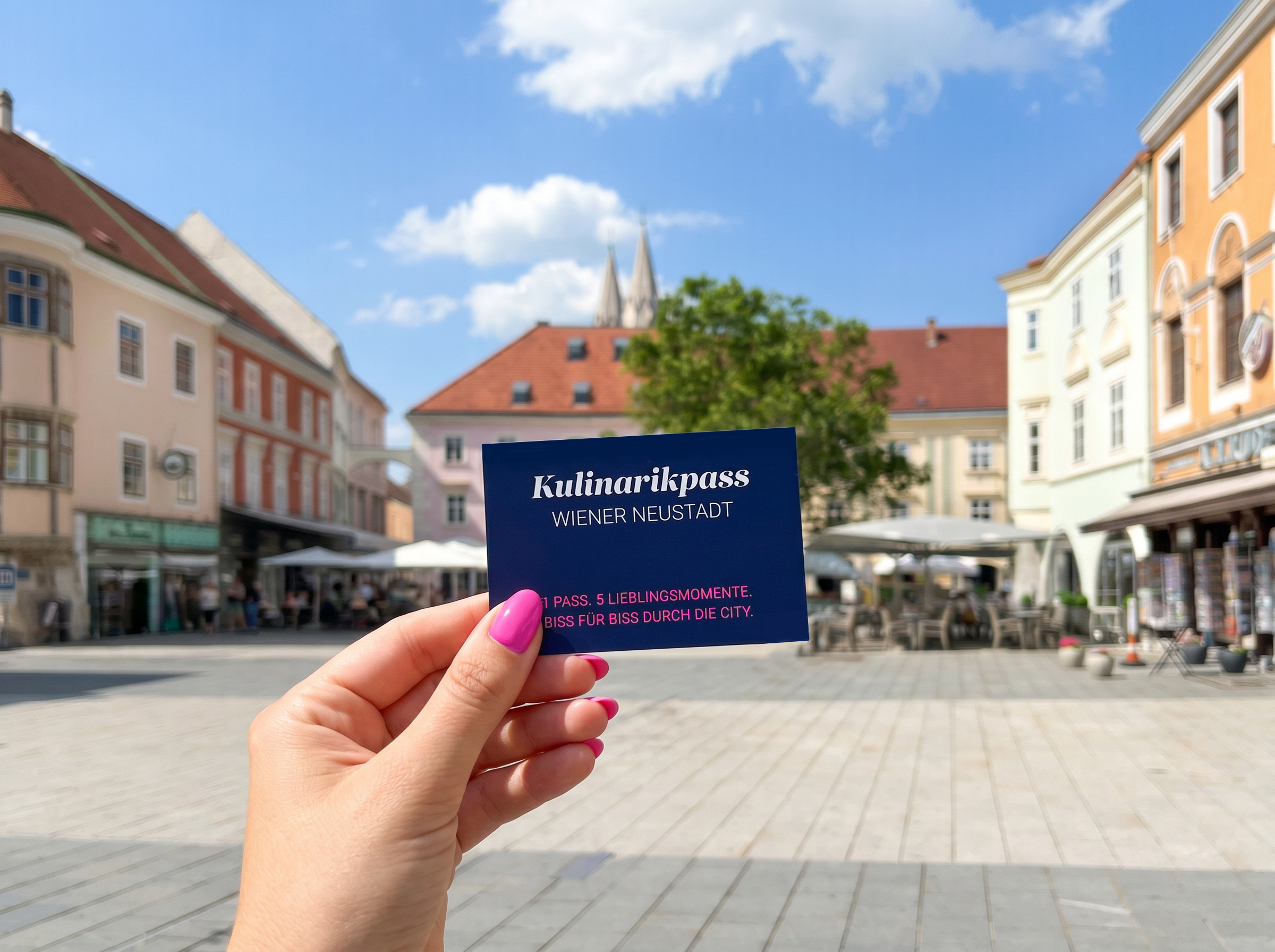 Kulinarikpass, der von einer Hand am Hauptplatz gezeigt wird