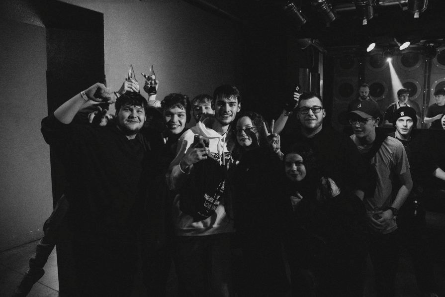 Das Schwarz-Weiß-Foto zeigt einige junge Menschen. Diese wirken ausgeglichen und feiern. 