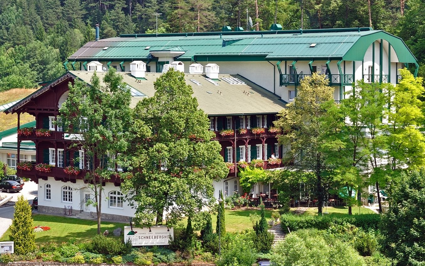 Ein großes Hotelgebäude mit grünen Dächern und Balkonen, umgeben von Bäumen und Natur.