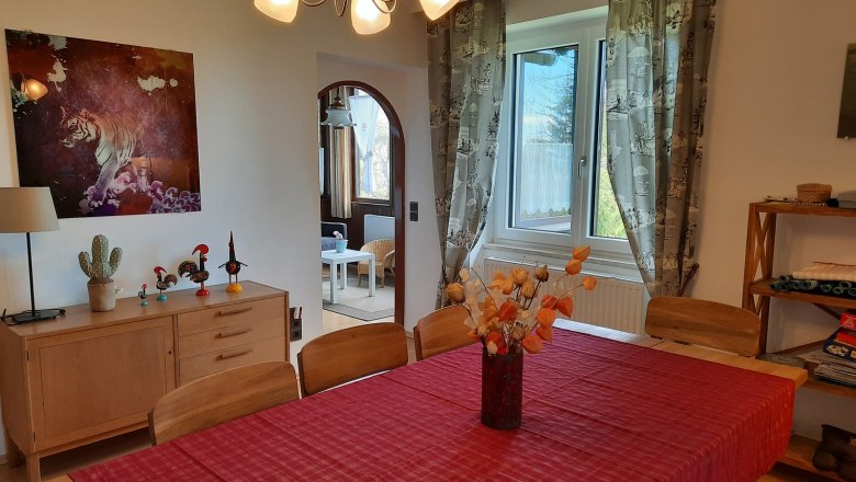 Esszimmer mit rotem Tischläufer, Holzmöbeln und Tigerbild an der Wand.