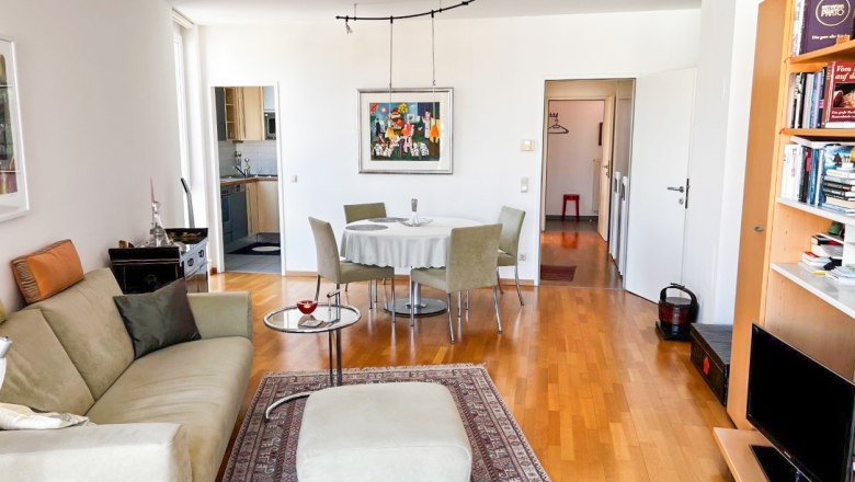 Wohnzimmer mit Sofa, Teppich, Esstisch und Bücherregal.