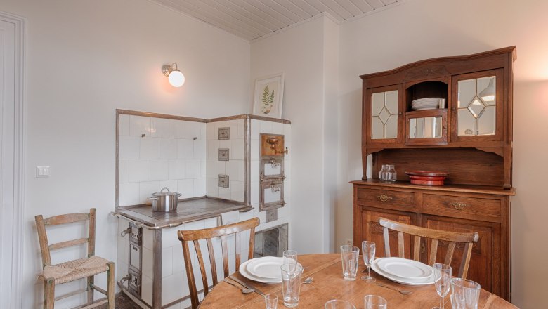 Vintage Küche mit Holzschrank, altem Herd und gedecktem Tisch.