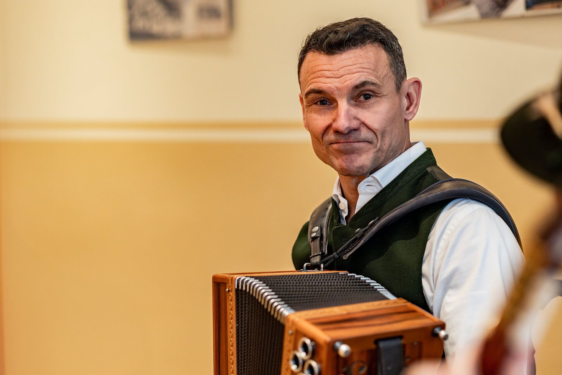 Ein Musiker mit Ziehharmonika schmunzelt.