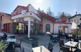 Außenansicht einer Café-Bar mit Terrasse und Sitzgelegenheiten im Freien.