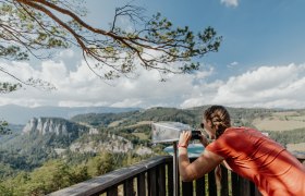 Frau schaut durch emen viewer auf eine Berglandschaft am Semmering Bahnwanderweg.