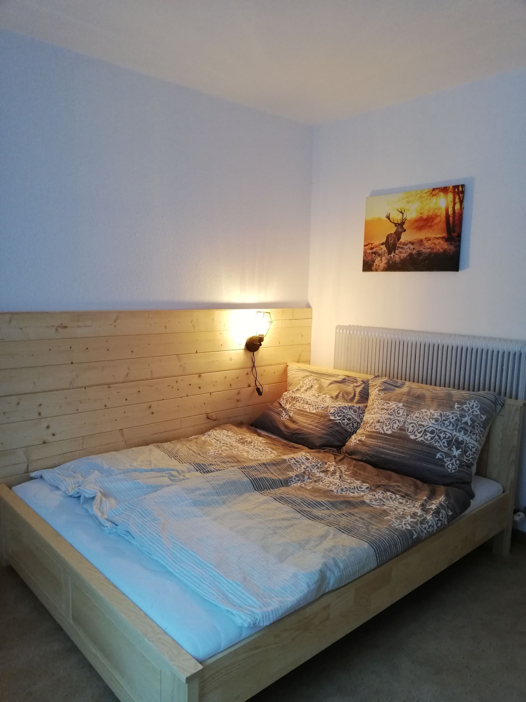 Doppelzimmer mit Holzbett und Hirschbild an der Wand.