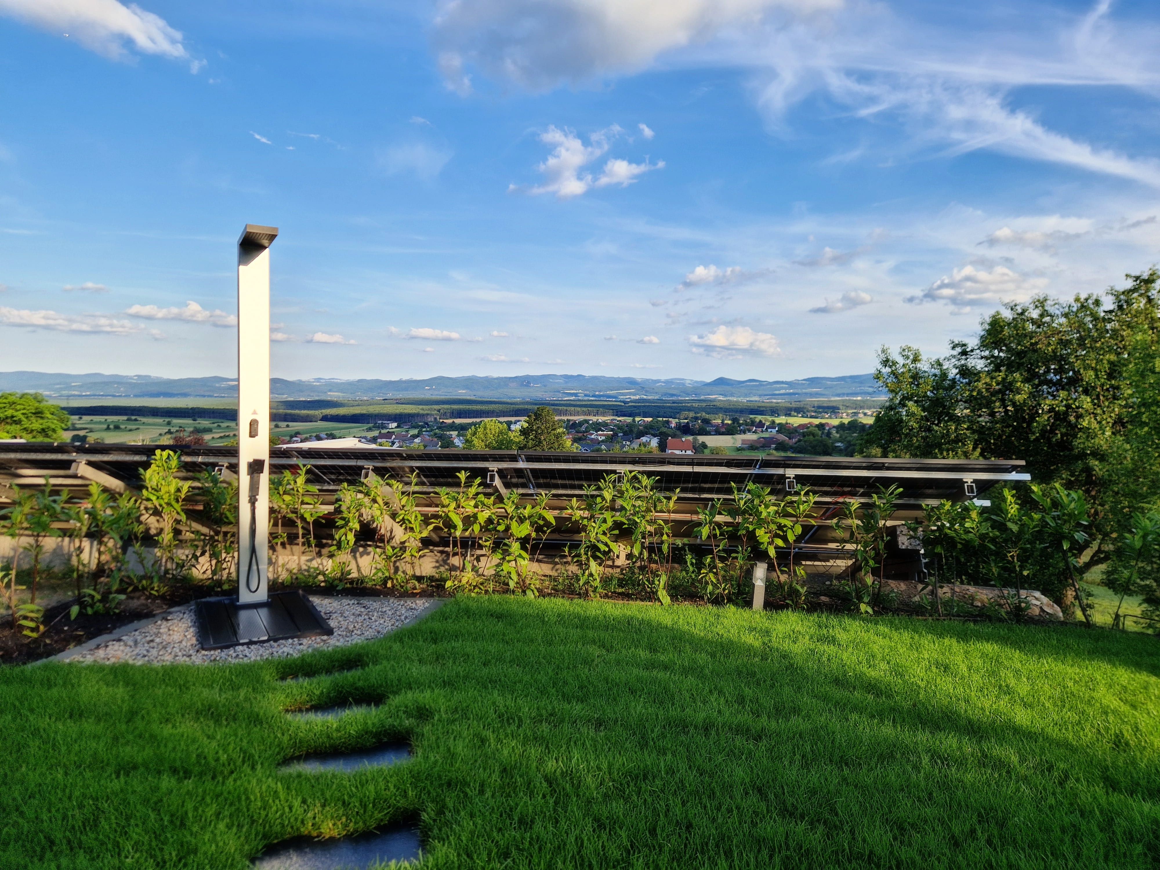 Solar-Dusche im Garten mit Blick auf Landschaft und blauen Himmel.