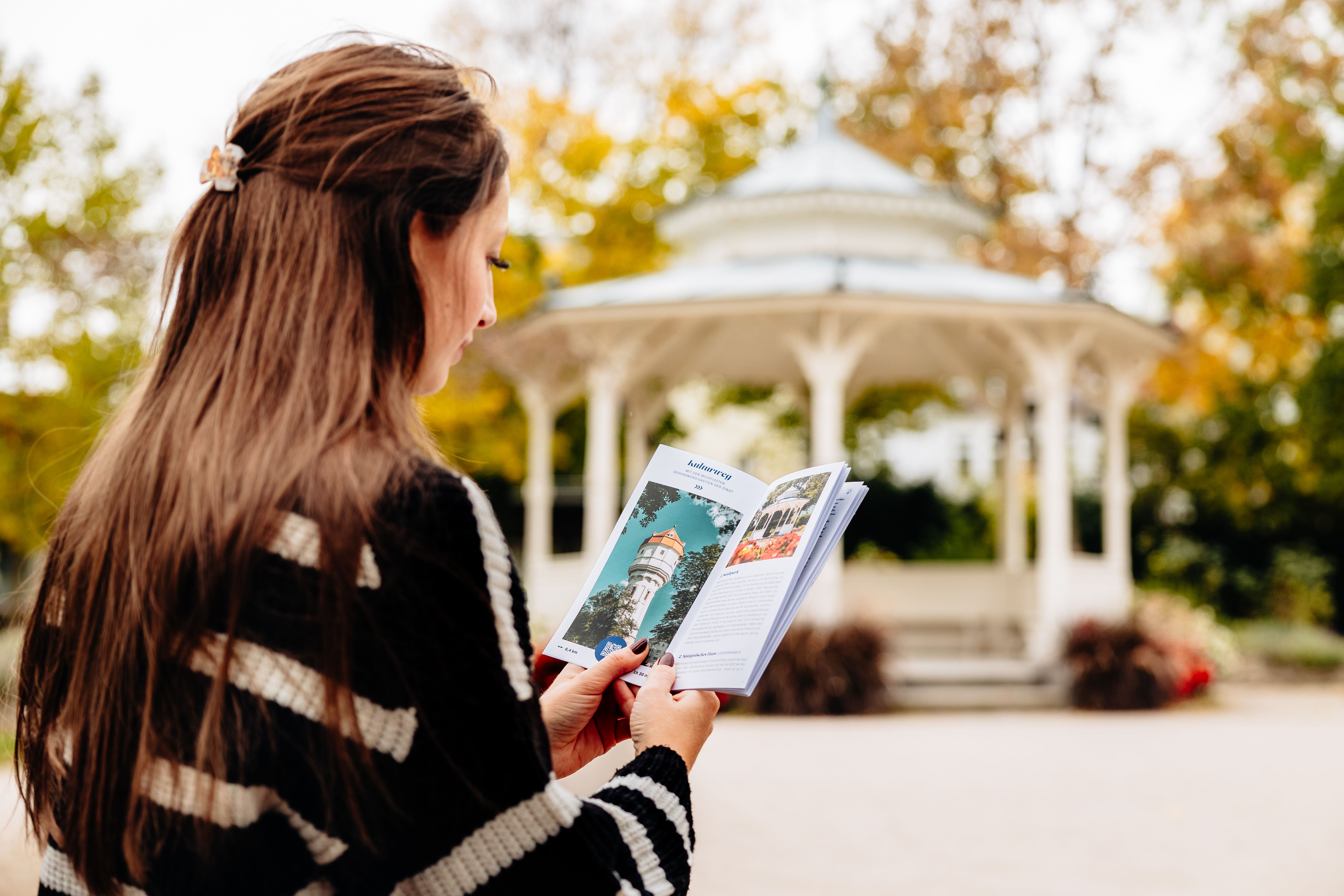 Frau liest einen Flyer vor einem Pavillon. 